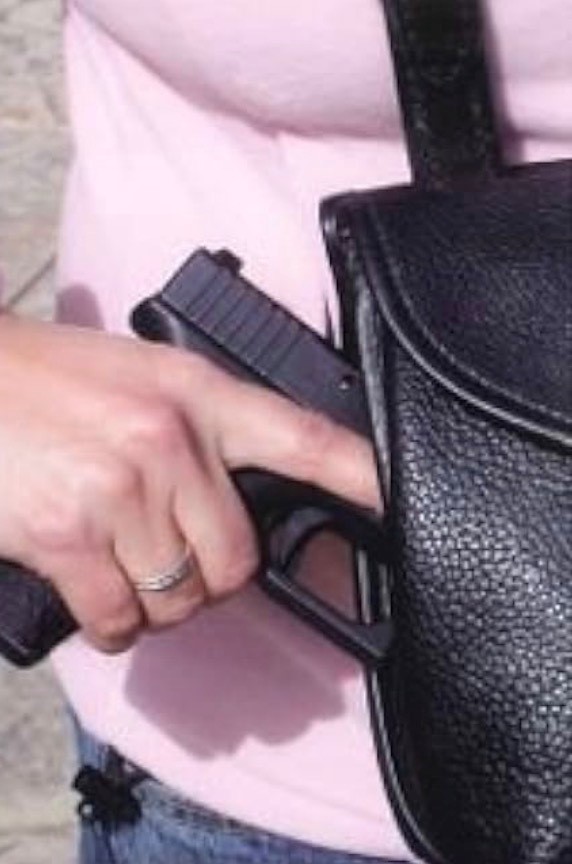 Person demonstrating off-body concealed carry with a firearm near a purse